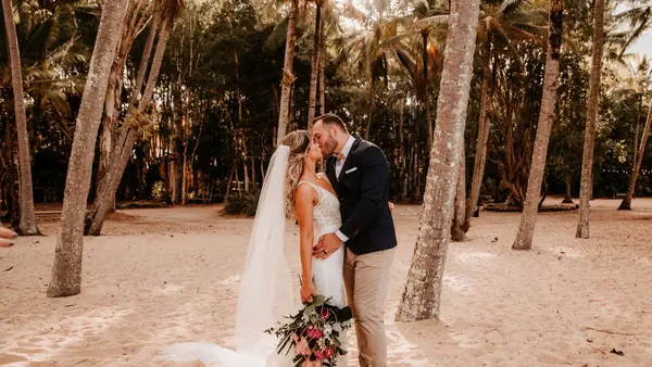 Bride and groom embracing under beach palms