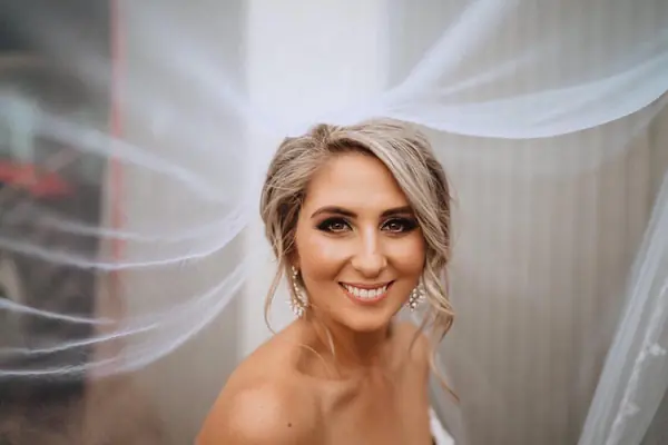 Smiling blonde bride beneath her veil