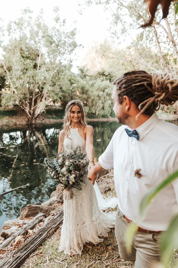 Bride and groom walking beside a lake
