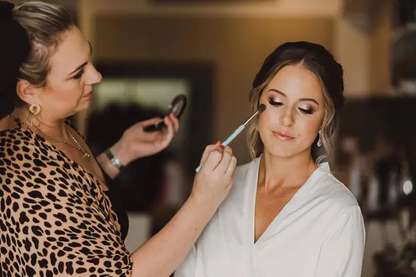 Carly doing a bride's makeup by the window