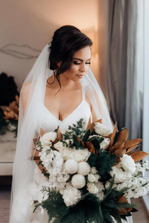 Dark-haired bride holding a white rose bouquet