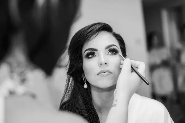 Black and white portrait of a bride's makeup application