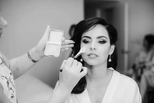 Black and white close-up of bridal makeup being applied