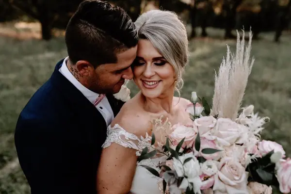 Bride with a pampas and protea bouquet beside the groom