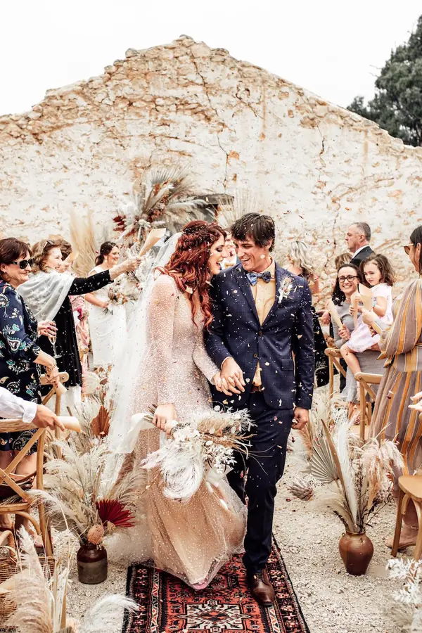 Newlyweds walking up the aisle as guests cheer