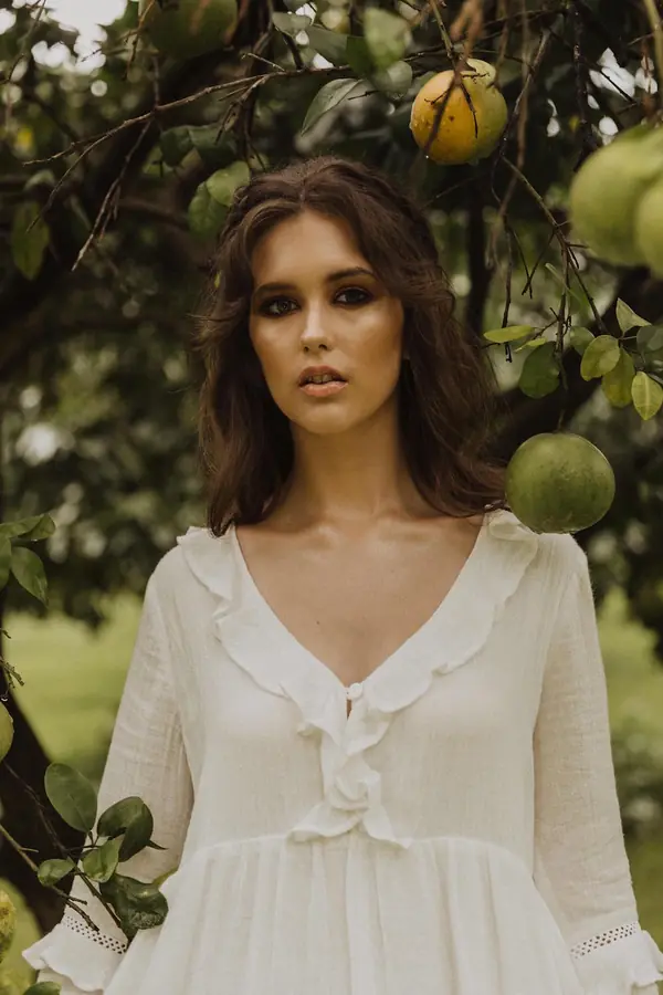 Model in a white ruffled dress beneath a citrus tree