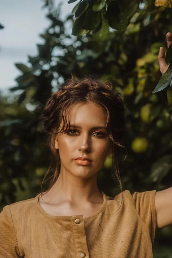 Model in a tan linen dress among fruit trees