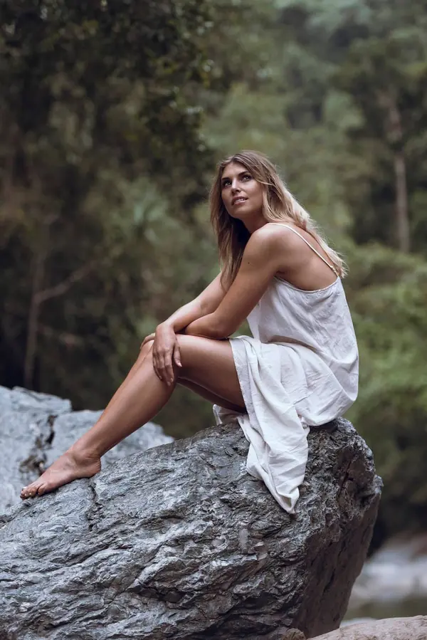 Model seated on a boulder beside a creek