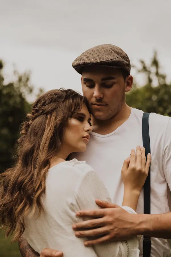 Couple in an orchard, the man in braces and a flat cap
