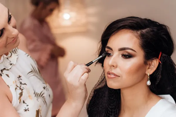 Carly applying eyeshadow to a bride